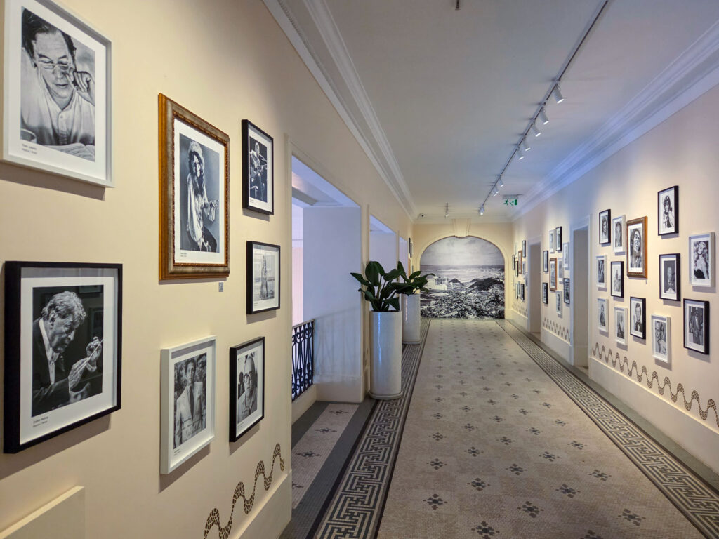 Hallway gallery of black-and-white portraits and historical photos at Belmond Copacabana Palace, highlighting its cultural legacy as a Rio de Janeiro luxury hotel ©Stephanie Dosch | theViatrix Luxury Travel