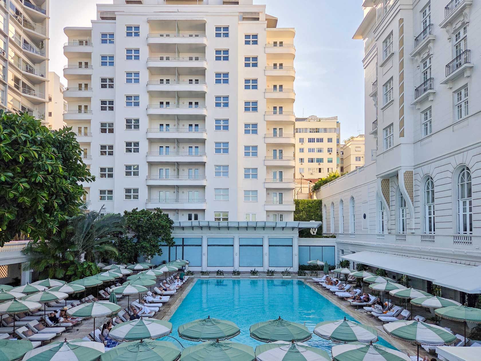 Elegant poolside scene with green-striped umbrellas at Belmond Copacabana Palace, one of the top luxury hotels in Rio de Janeiro, Brazil ©Stephanie Dosch | theViatrix Luxury Travel