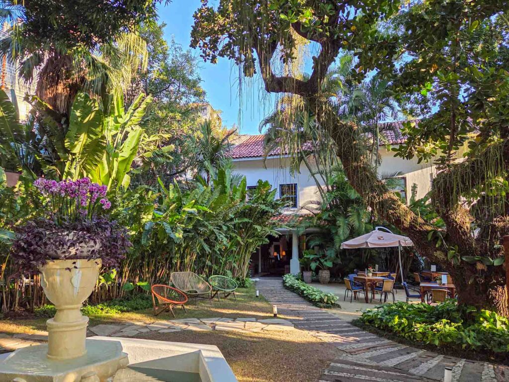 Shaded garden courtyard with lush greenery and outdoor dining at Santa Teresa Hotel RJ - MGallery in Rio de Janeiro ©Stephanie Dosch | theViatrix Luxury Travel